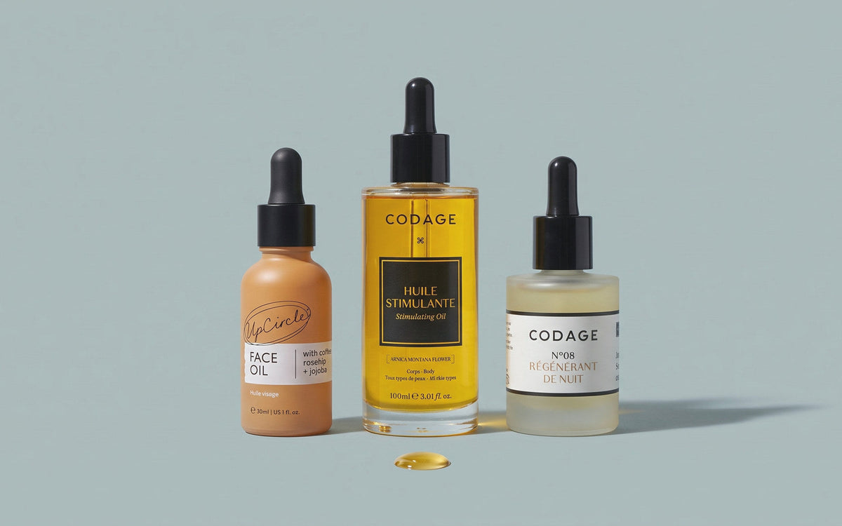 UpCircle Ansigtsolie med Kaffe & Hybenolie, CODAGE Stimulating Oil og CODAGE Serum No. 8 Night Rejuvenation på gråblå baggrund