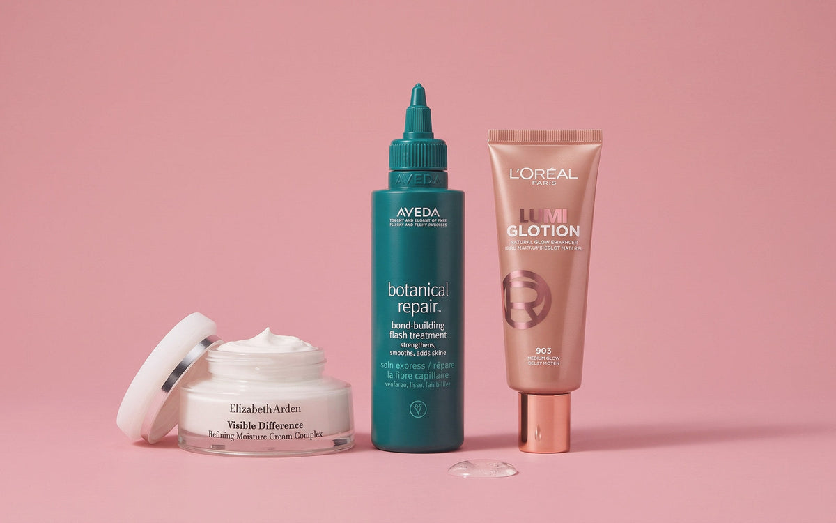 Elizabeth Arden Visible Difference Refining Moisture Cream Complex, Aveda Botanical Repair Bond Building Flash Treatment og L'Oréal True Match Lumi Glotion på lyserød baggrund