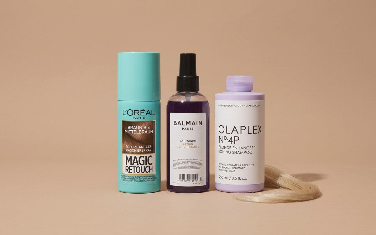 L'Oréal Paris Magic Retouch rodspray, Balmain Paris Hair Couture Ash Toner og Olaplex No. 4P Blonde Enhancer Toning Purple Shampoo på sand baggrund