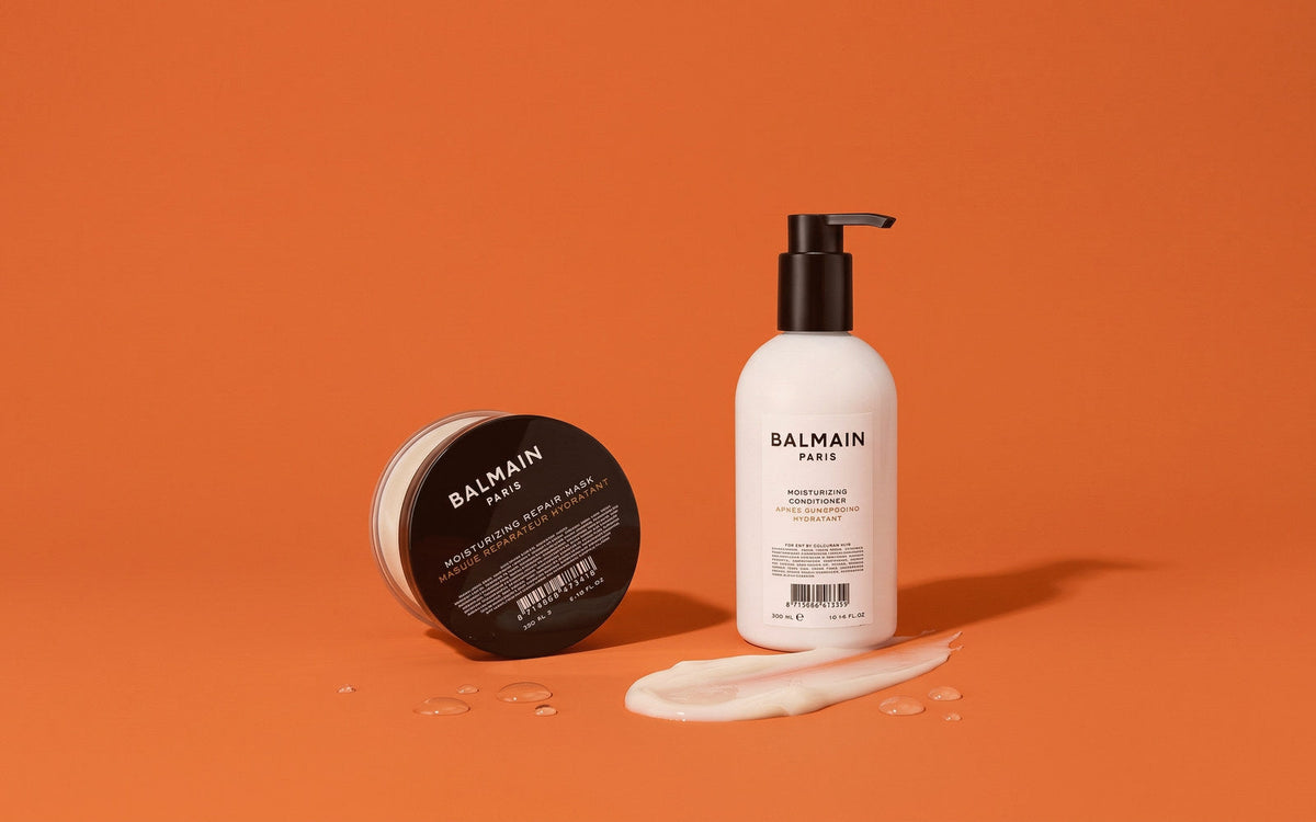Balmain Moisturizing Repair Mask i sort krukke og Moisturizing Conditioner i hvid pumpeflaske på orange baggrund