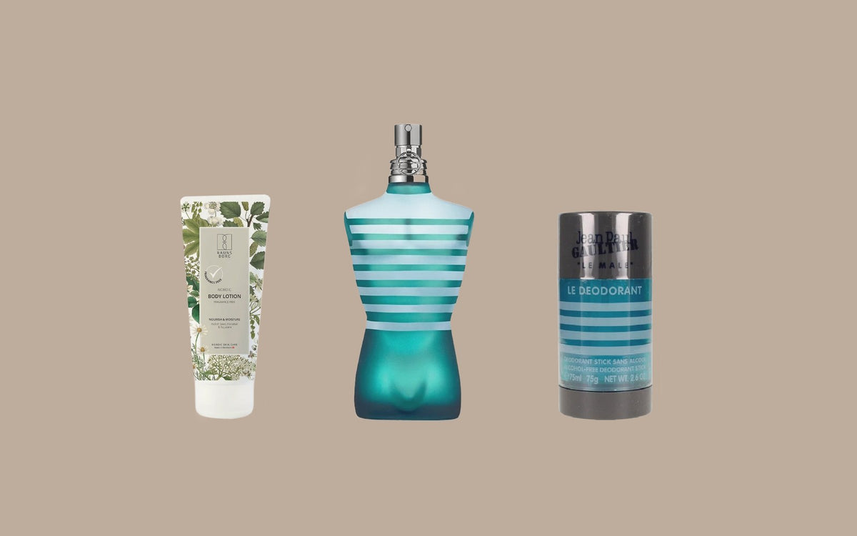 Jean Paul Gaultier Le Male eau de toilette mellem en parfumefri Raunsborg bodylotion og en Le Male deodorantstift på sandfarvet baggrund