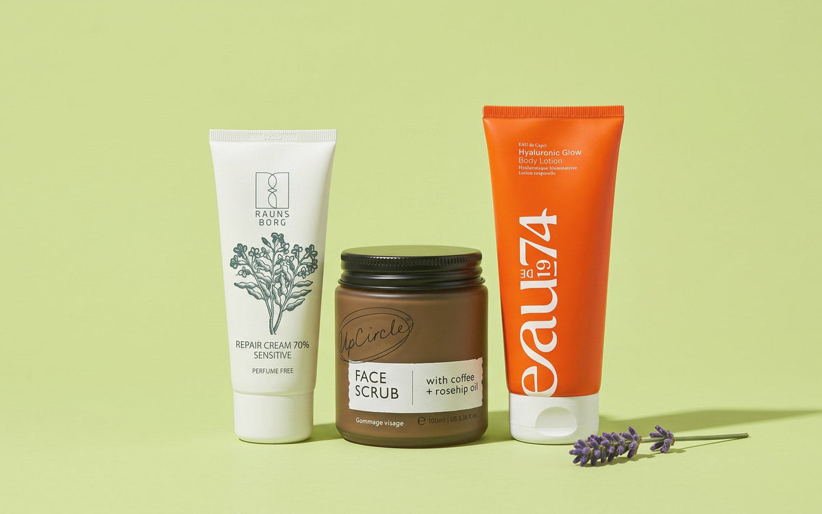 Raunsborg Sensitive Repair Cream 70 Parfumefri, UpCircle Coffee Face Scrub og EAUde1974 Hyaluronic Glow Body Lotion på lysegrøn baggrund